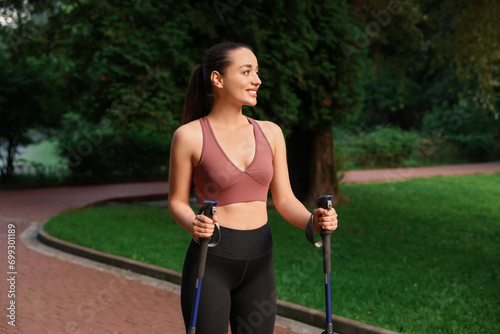 Young woman practicing Nordic walking with poles outdoors