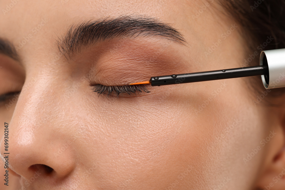 Woman applying serum onto her eyelashes, closeup. Cosmetic product