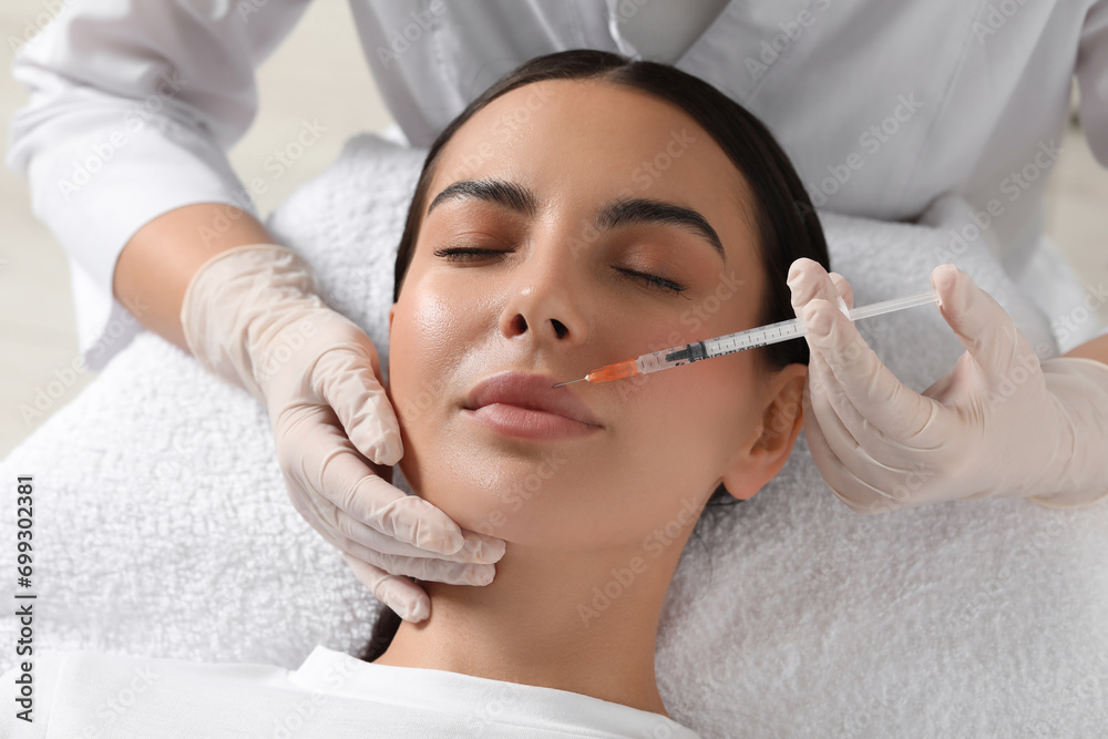 Doctor giving lips injection to young woman in clinic. Cosmetic surgery Doctor giving lips injection to young woman in clinic. Cosmetic surgery