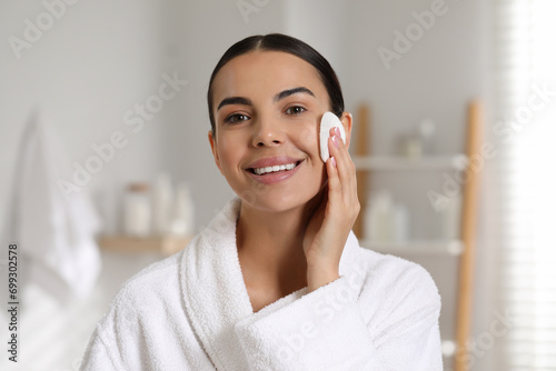Beautiful woman removing makeup with cotton pad in bathroom photo