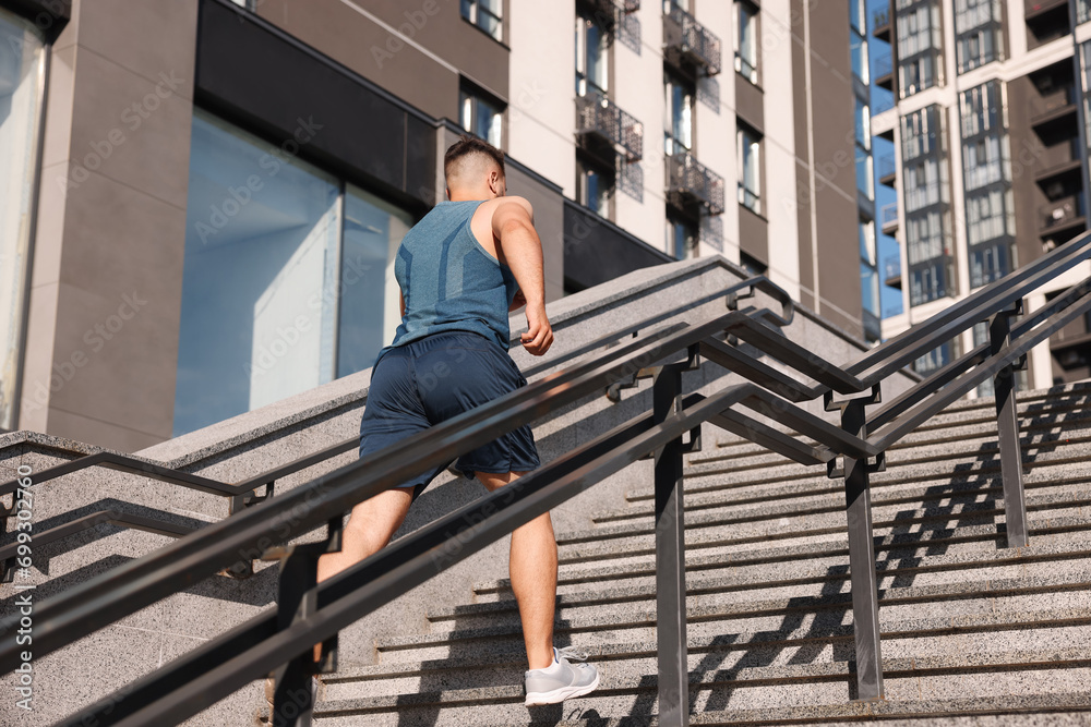 Man running up stairs outdoors on sunny day, low angle view