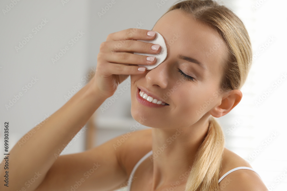Smiling woman removing makeup with cotton pad indoors, closeup Smiling woman removing makeup with cotton pad indoors, closeup