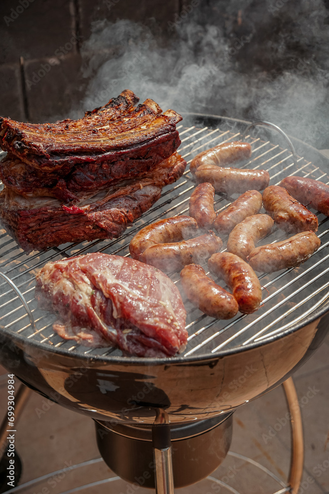 Beef steak and pork meat on the barbecue. Grilled meat surrounded by smoke. Food concept. High angle view of meat on barbecue grill Beef steak and pork meat on the barbecue. Grilled meat surrounded by smoke. Food concept. High angle view of meat on barbecue grill