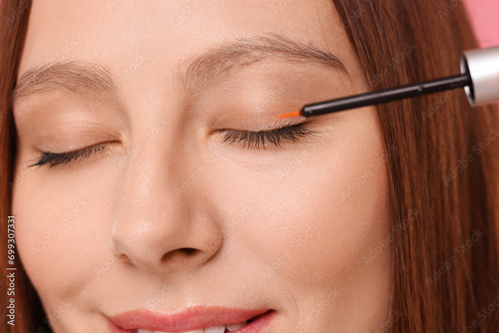 Woman applying serum onto eyelashes, closeup view