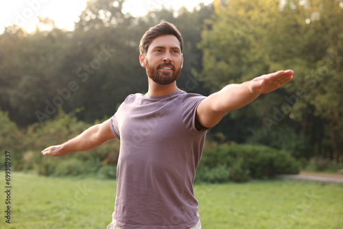 Attractive man practicing yoga in park on sunny day