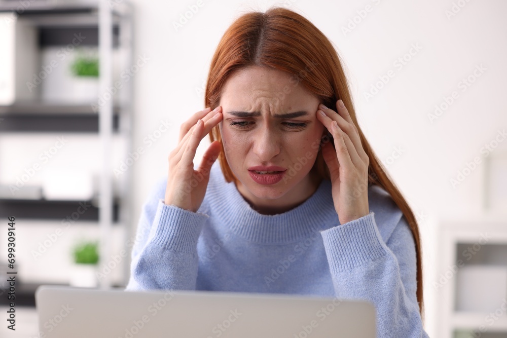 Woman suffering from headache at workplace in office Woman suffering from headache at workplace in office