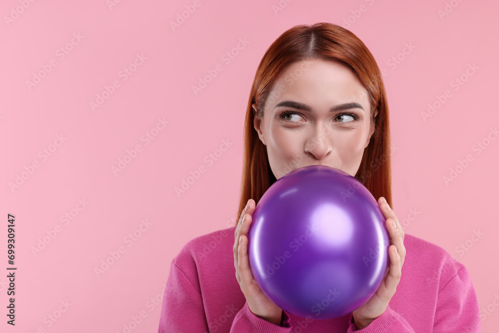 Woman inflating purple balloon on pink background, space for text Woman inflating purple balloon on pink background, space for text