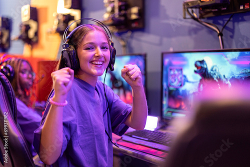 Portrait of young gamer girl playing online video games celebrating that she is winning the game photo