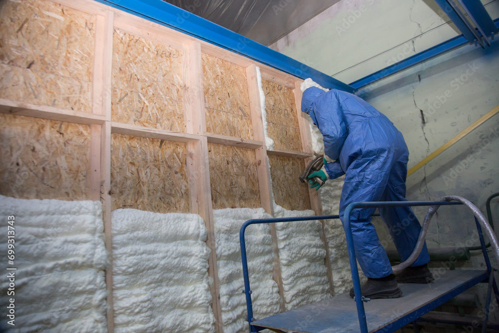 Insulation of walls with foam, energy and heat saving of walls, worker treats walls with foam