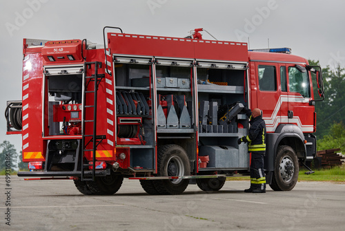 A firefighter meticulously prepares a modern firetruck for a mission to evacuate and respond to dangerous situations, showcasing the utmost dedication to safety and readiness in the face of a fire