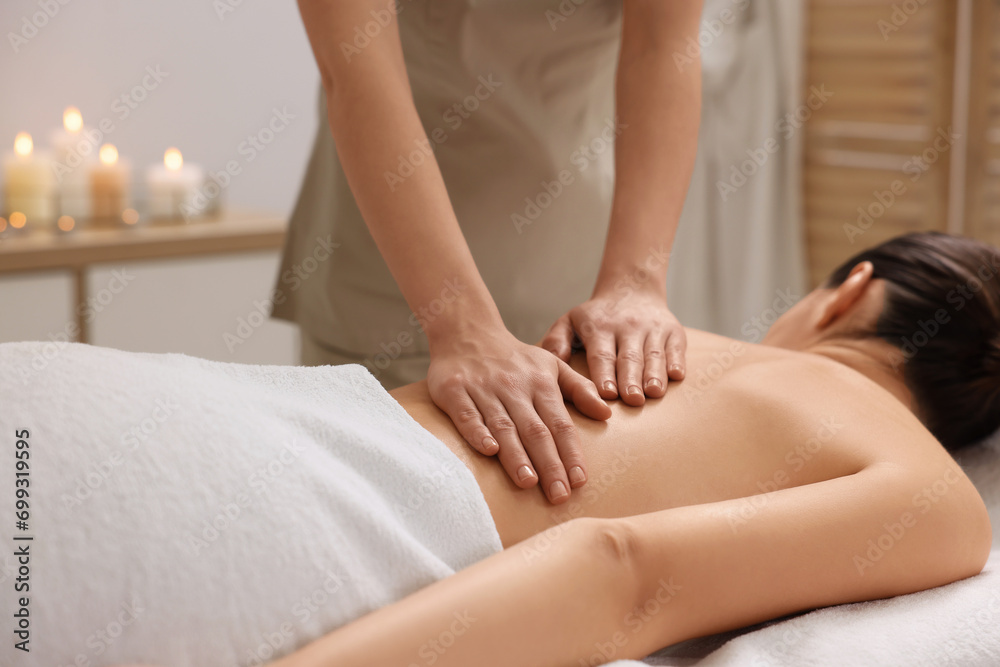 Woman receiving back massage on couch in spa salon