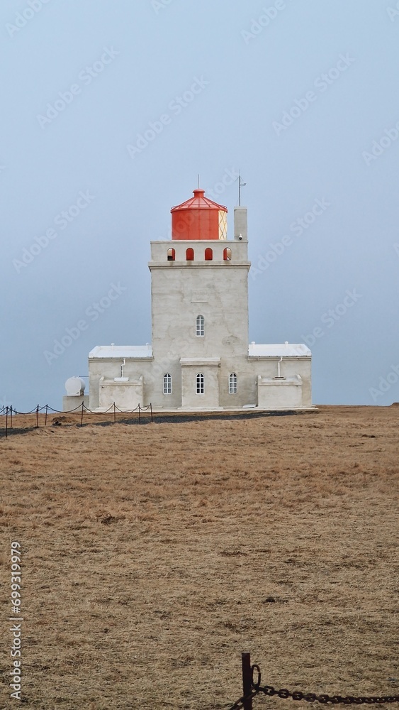 Icelandic Dyrholaey historical tower with beautiful lighthouse on mainland to help guide sailors. Navigation tower with light used near icelandic cliff coastline, arctic shore ocean guidance.