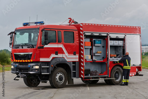 A firefighter meticulously prepares a modern firetruck for a mission to evacuate and respond to dangerous situations, showcasing the utmost dedication to safety and readiness in the face of a fire