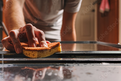 Unrecognizable man scrubbing the oven with a sponge,