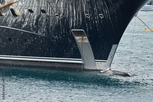 Sun glare on glossy board of mega yacht, anchor, tranquillity in port Hercules, bow of moored huge boat at sunny day, Monaco, Monte-Carlo photo