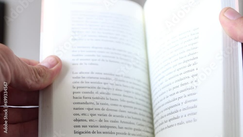 hand holding a book. pages goes slow at first and then faster. spanish text photo