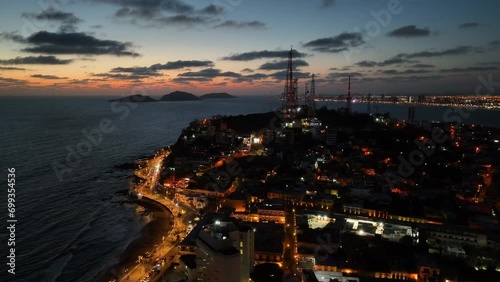 Aerial view orbiting a illuminated hill on the coast of Mazatlan, vibrant evening in Mexico photo