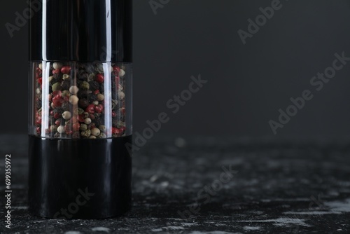 Pepper shaker on dark marble table, closeup. Space for text photo