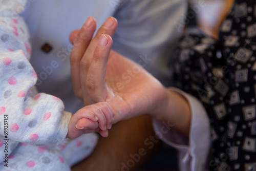 A lovely newborn baby grasping her mothers' finger trustfully and enthusiastically photo