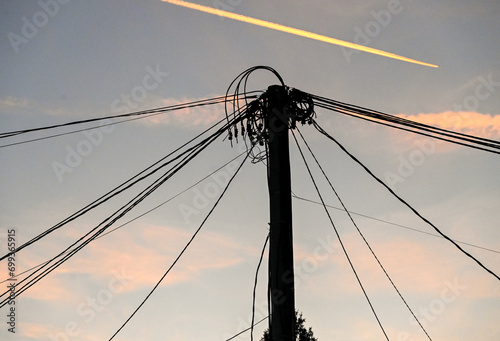 Lots of electrical cables on a pole during sunset with an airplane in the background. Electricity. Transmission of electric power. 