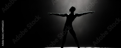 Silhouette of a male dancer performing an elegant mid-air leap on a dark stage with a dramatic spotlight.
