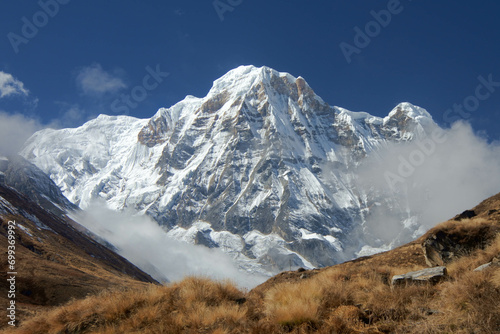 Stunning views of snow mountains, blue skies and large rocks along the track to Annapurna Base Camp.Keywords language: English