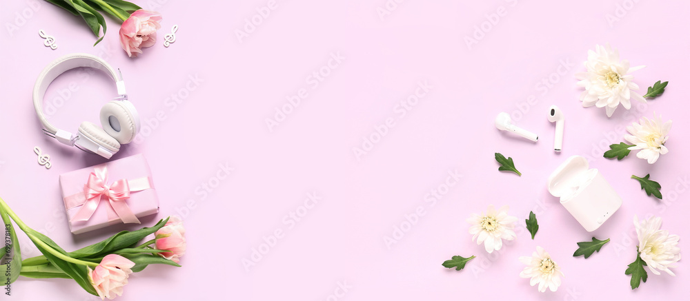 Modern headphones with earphones, gift and flowers on pink background with space for text