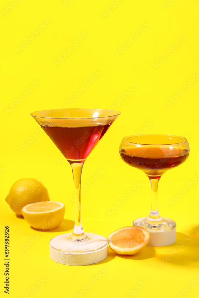 Glasses of Cosmopolitan cocktail with lemon on yellow background