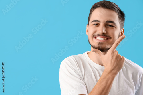 Handsome young man with healthy teeth on blue background. Dental care concept