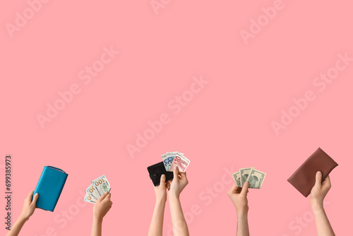 Female hands with credit cards, wallets and money on pink background