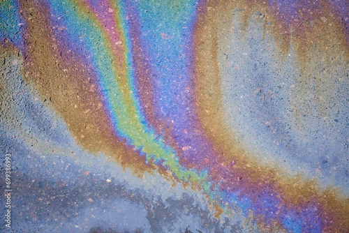 Gasoline spot on wet asphalt. Multi colored oil spill on asphalt road  abstract background  texture