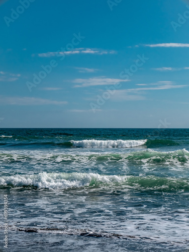 small waves on the beach with a bright blue sky 