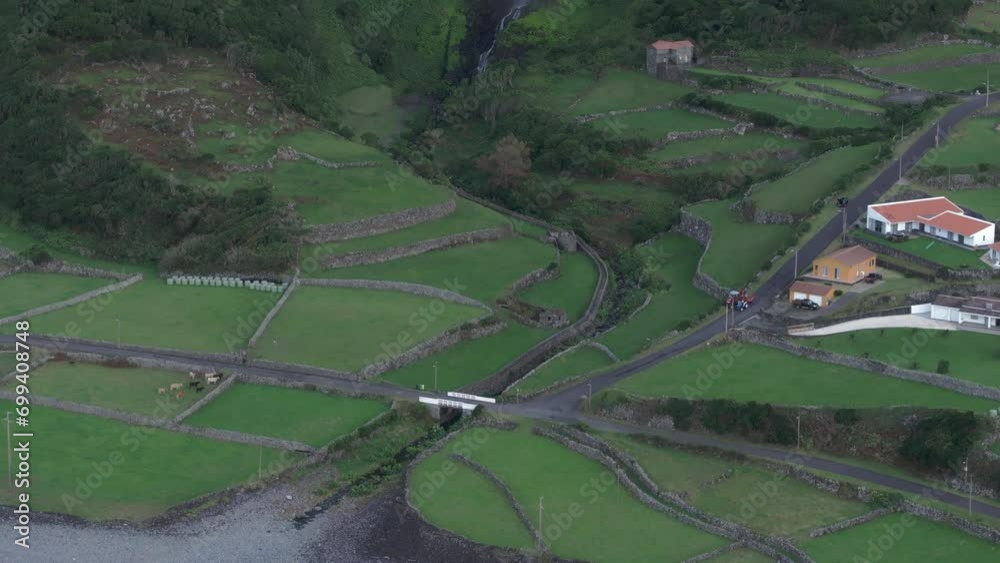 Aerial view tilting toward cascata do poco do bacalhau waterfall at Fajã Grande