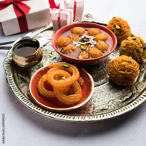 indian sweet jalebi imarti laddu and gujiya served together over white background photo