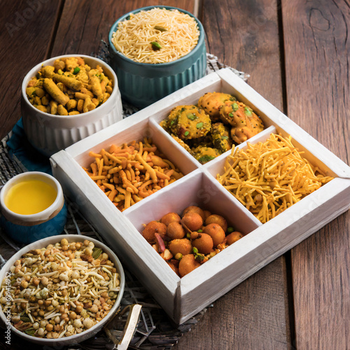 indian tea time snacks like sev, chivda, farsan, mixture, boondi, bakarwadi etc served in white wooden box with cells