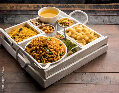 indian tea time snacks like sev, chivda, farsan, mixture, boondi, bakarwadi etc served in white wooden box with cells photo