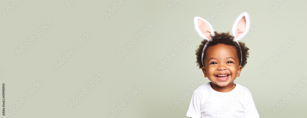 Horizontal banner of African American happy smiling young toddler boy with cute bunny rabbit ears on studio mint green background. Empty space place for text, copy paste Horizontal banner of African American happy smiling young toddler boy with cute bunny rabbit ears on studio mint green background. Empty space place for text, copy paste