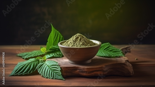 Mitragyna speciosa (kratom) leaves with medicinal products in the form of powder in a wooden cup with the wood texture as the background photo