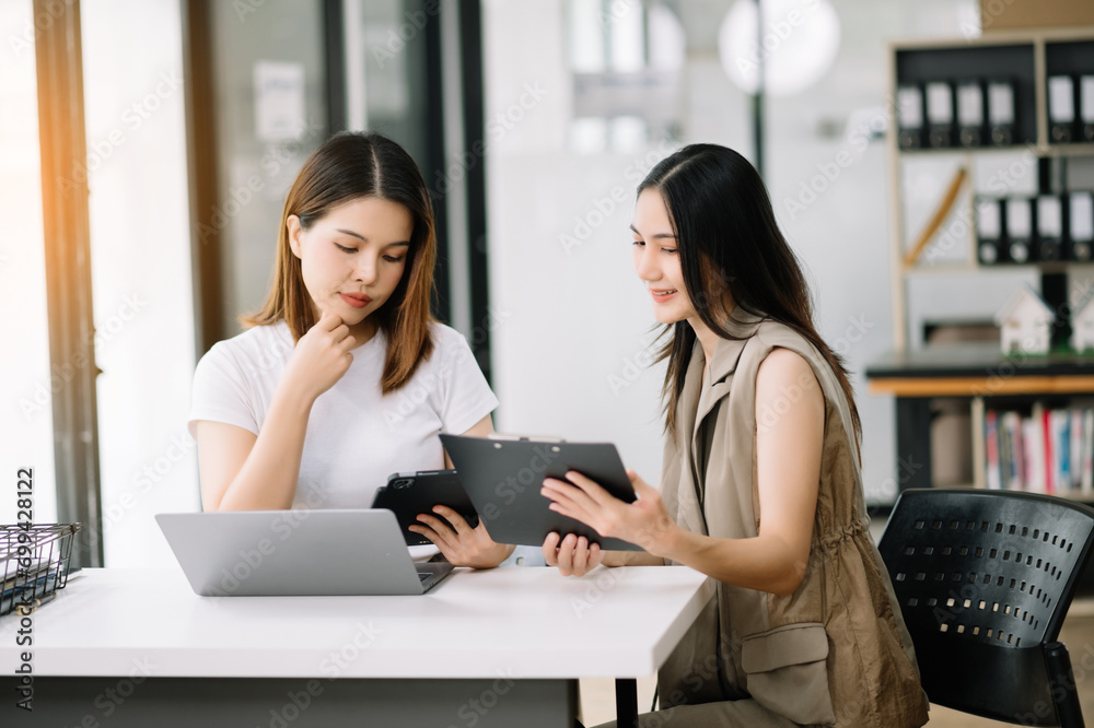 Two business workers talking on the smartphone and using laptop at the office.. Two business workers talking on the smartphone and using laptop at the office..