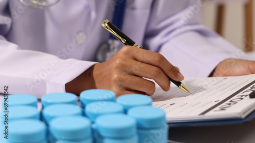 Initial AI illustration of a close-up of a female doctor's hand signing a medical document on a clipboard. and recommending certain medicines to patients on a laptop photo