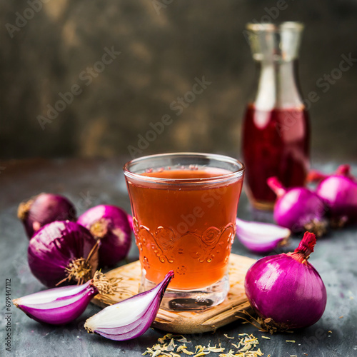 medicinal onion juice/syrup in a glass with raw onions. selective focus photo