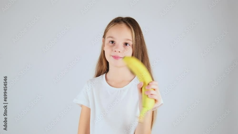 Close-up preteen girl enjoying healthy food. Portrait little girl in her 7 holding delicious banana with white isolated background Close-up preteen girl enjoying healthy food. Portrait little girl in her 7 holding delicious banana with white isolated background