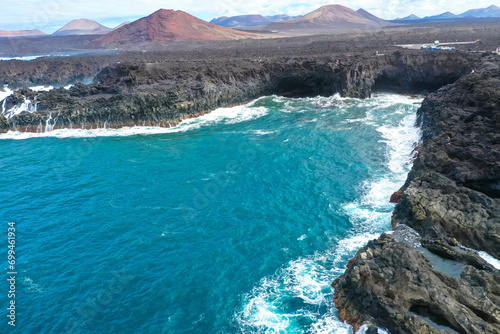 Panoramic aerial view of Los Hervideros. Southwest coast, rugged volcanic coast, strong surf, sea caves, red lava hills. Lanzarote, Canary Islands, Spain photo