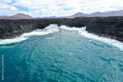 Panoramic aerial view of Los Hervideros. Southwest coast, rugged volcanic coast, strong surf, sea caves, red lava hills. Lanzarote, Canary Islands, Spain