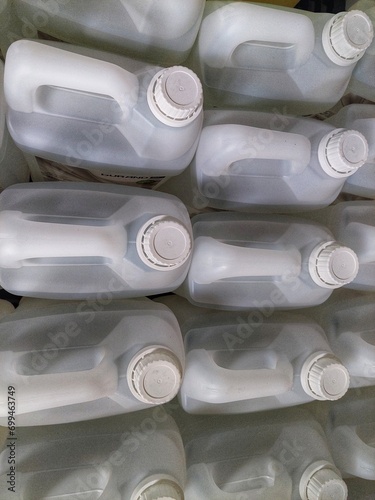lots of white jerry cans filled with hand soap and sanitizer liquid in warehouse	