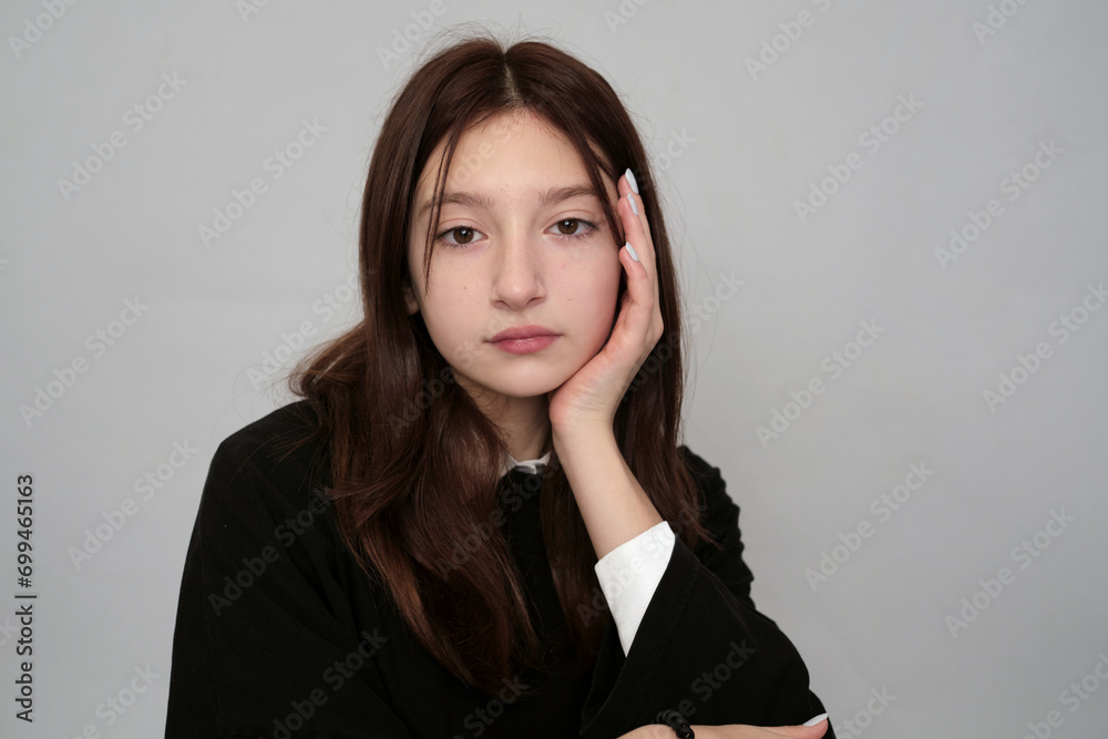 Teen girl in a black hoodie leans thoughtfully on her hand, exuding a contemplative and modern style.