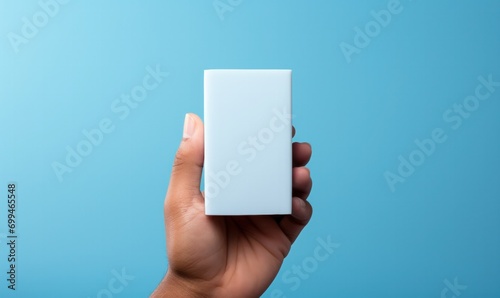 Hand holding small white rectangular box on blue background
