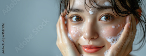 Close-up portrait of an asian woman, hands washing face with soap foam, smiling, ideal for a landscape web banner, generative ai photo