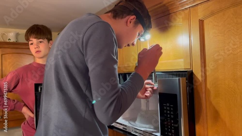 Teen boys dong home repair on microwave in kitchen photo
