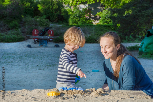Obraz na płótnie Mother and cute little child boy having fun playing with sand and colorful toys in the park, beautiful summer sunny day in children playground. Selective focus w salonie